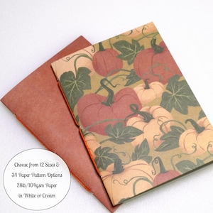 May include: A notebook with a pumpkin and vine pattern on the cover, featuring a brown spine and binding. A circular text overlay states: Choose from 12 Sizes & 34 Paper Pattern Options, 28lb/104gsm Paper in White or Cream.