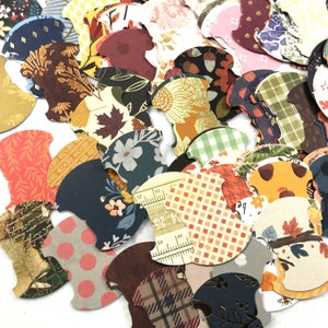 May include: Assortment of colorful paper craft supplies in various patterns, including plaid, floral, and geometric designs. The paper is cut into the shape of spools of thread.