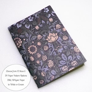 May include: A rectangular notebook featuring a dark purple and black background with a dense floral pattern of light purple and peach-colored flowers and leaves. Text on the image reads: Choose from 12 Sizes & 34 Paper Pattern Options 28lb/104gsm Paper in White or Cream.