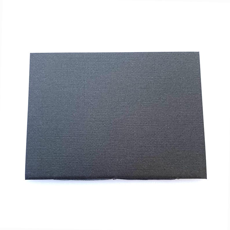 May include: A rectangular, black card with a textured surface. The card is set against a white background, providing a stark contrast that highlights its dark color and subtle texture. The card's edges are clean and well-defined.