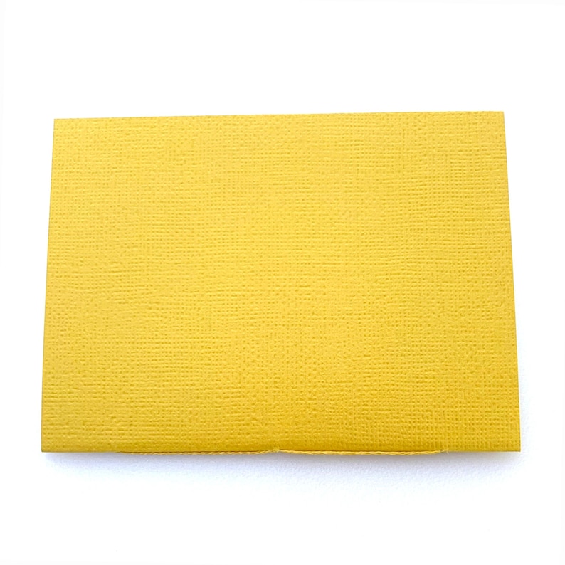 May include: A yellow card stock paper with a textured surface.
