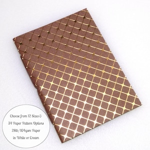 May include: A rectangular sheet of brown paper featuring a repeating gold grid pattern with rounded corners at each intersection. A circular white label includes the text: Choose from 12 Sizes & 34 Paper Pattern Options 28lb/104gsm Paper in White or Cream.