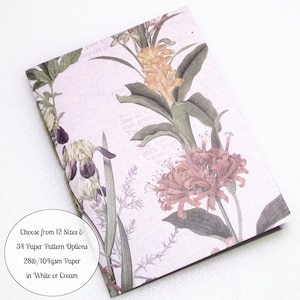 May include: A rectangular notebook featuring a light purple background with a botanical illustration of yellow, purple, and reddish-pink flowers and green leaves. Text on the cover reads: Choose from 12 Sizes & 34 Paper Pattern Options 28lb/104gsm Paper in White or Cream.
