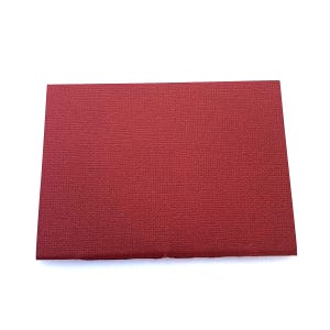 May include: A rectangular, textured, deep red cardstock paper. The paper has a slightly rough surface and is a solid, uniform color. The edges of the paper are clean and straight, and the paper is set against a white background.