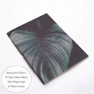May include: A rectangular notebook featuring a dark green and black botanical leaf print on the cover. A circular white graphic overlay includes the text: Choose from 12 Sizes & 34 Paper Pattern Options 28lb/104gsm Paper in White or Cream.