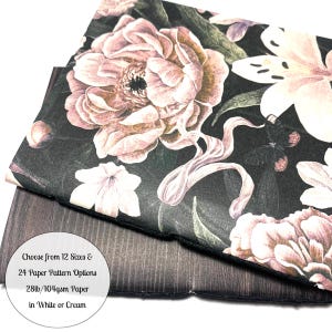 May include: Two sheets of paper with a floral pattern. The top sheet is black with pink and white flowers and butterflies. The bottom sheet is a dark brown wood grain. The text on the paper reads: "Choose from 12 Sizes & 24 Paper Pattern Options 28lb/104gsm Paper in White or Cream"