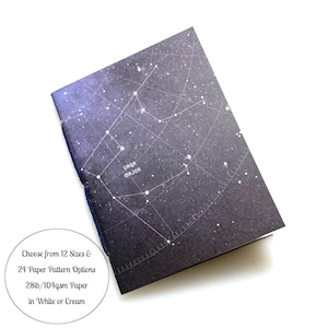 May include: A black notebook with a constellation of stars printed on the cover. The constellation is labeled "URSA MAJOR". The notebook is closed and the cover is slightly folded at the top right corner.