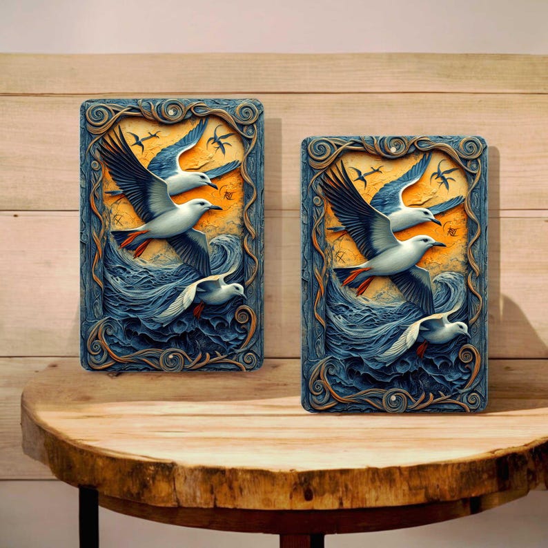 May include: Two rectangular wall art pieces featuring a stylized depiction of seagulls in flight over ocean waves. The artwork has a blue, orange, and white color palette, with a decorative border. The pieces are displayed on a wooden table.