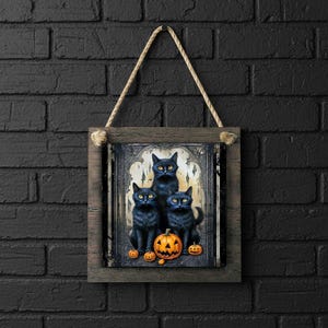May include: Wooden framed Halloween wall art featuring three black cats with yellow eyes, a carved pumpkin, and smaller pumpkins. The artwork is suspended by a natural rope. The frame has a rustic, weathered appearance, perfect for seasonal decor.