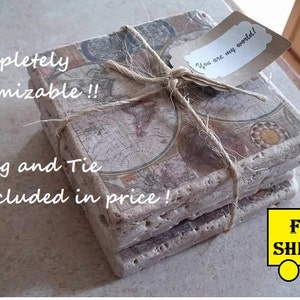 May include: Set of four square coasters with a vintage world map design. The coasters are made of a light brown material and have a rough texture. The coasters are tied together with twine and a gift tag that reads "You are my world!"