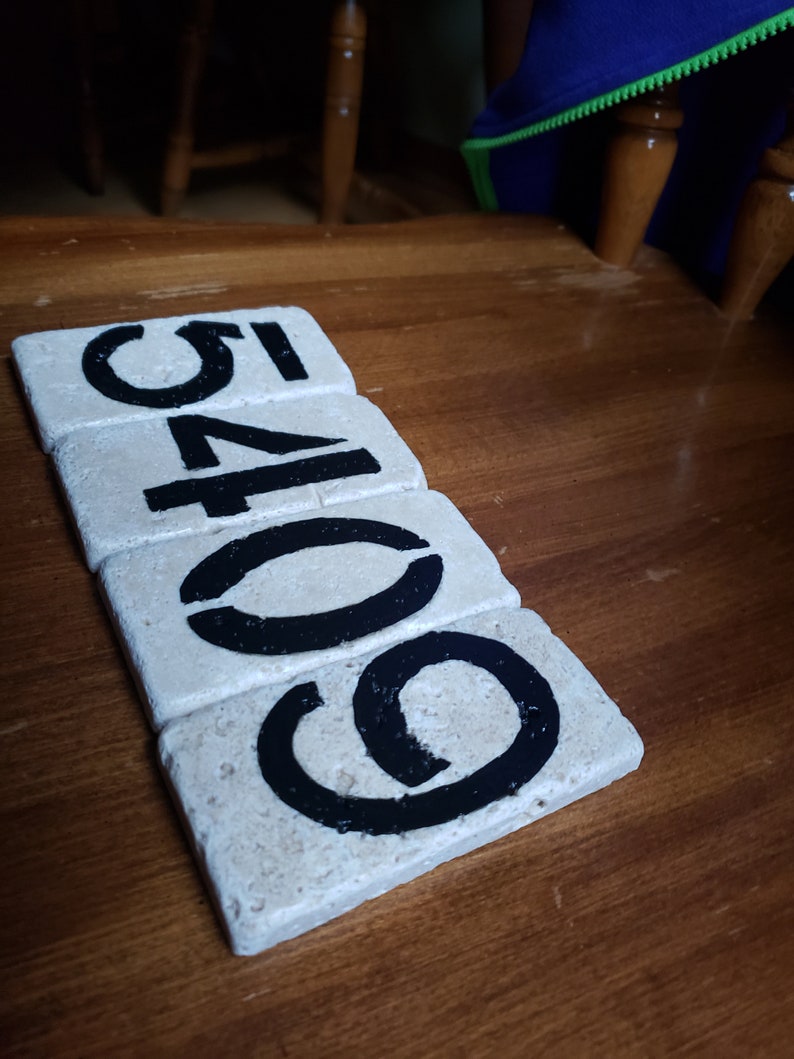 May include: Five white tiles with black numbers painted on them. The numbers spell out "60541".