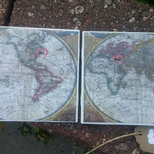 Pode incluir: Duas bases quadradas com um design de mapa-múndi vintage. Cada base apresenta um coração com o nome de uma cidade e uma linha tracejada. Uma base mostra as Américas, a outra a Europa e a África.