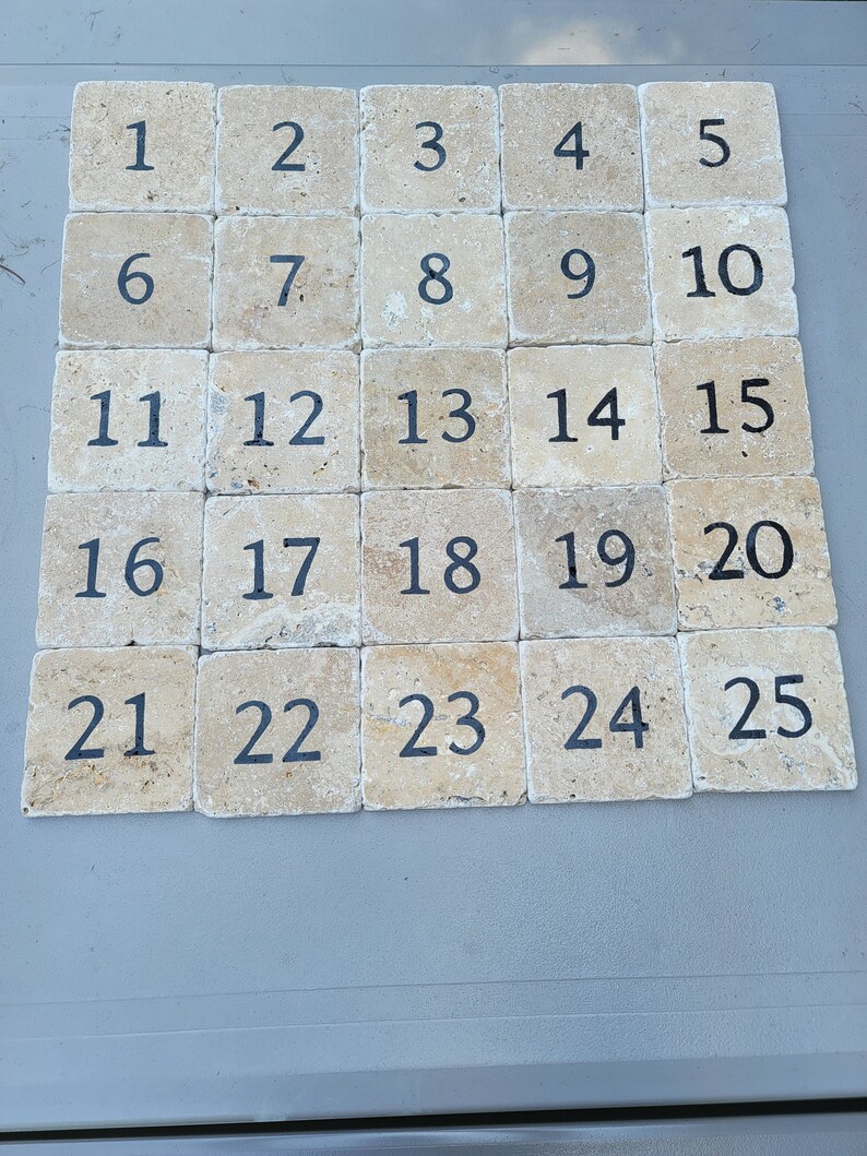 May include: Twenty-five square tiles with a beige background and black numbers from 1 to 25.