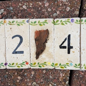 May include: Five ceramic tiles with a floral design border, each tile has a black number painted on it, the numbers are 1245, the tiles are arranged in a row.