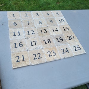 May include: A set of 25 beige square tiles with black numbers from 1 to 25. The tiles are arranged in a grid pattern.