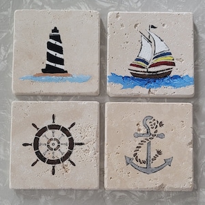 May include: Set of four square ceramic coasters with nautical themed designs. The coasters feature a lighthouse, a sailboat, a ship's wheel, and an anchor.