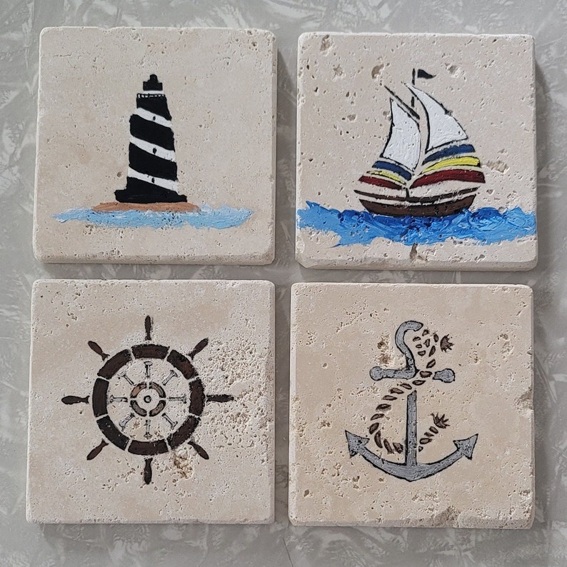 May include: Set of four square ceramic coasters with nautical themed designs. The coasters feature a lighthouse, a sailboat, a ship's wheel, and an anchor.