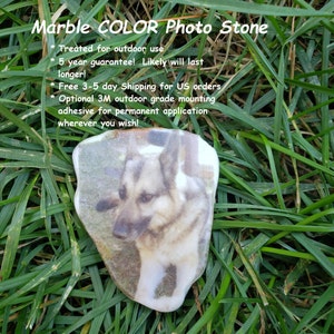 May include: A close-up of a white marble stone with a photo of a German Shepherd dog printed on it. The stone is sitting on a bed of green grass. The text "Marble COLOR Photo Stone" is at the top of the image. The text "Treated for outdoor use", "5 year guarantee! Likely will last longer!" and "Free 3-5 day Shipping for US orders" is also visible in the image.