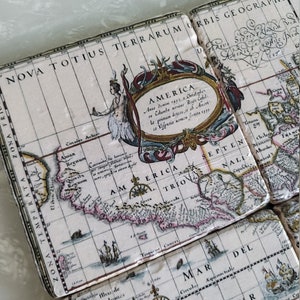 Puede incluir: Un juego de posavasos cuadrados con un dise&ntilde;o de mapa antiguo. Los posavasos presentan un fondo color crema con un mapa detallado de las Am&eacute;ricas, incluyendo texto e ilustraciones. El mapa est&aacute; enmarcado por bordes y texto decorativos.