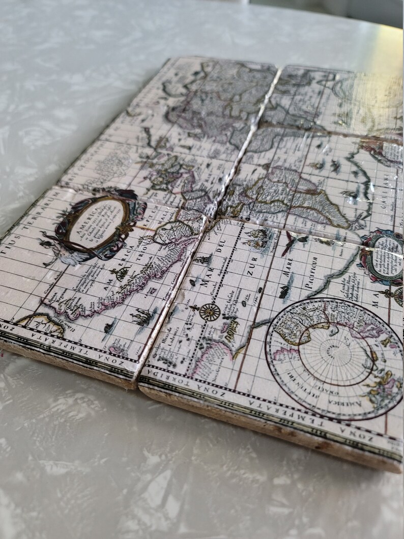 Puede incluir: Juego de cuatro posavasos cuadrados con un dise&ntilde;o de mapa del mundo vintage. Los posavasos tienen un fondo crema con ilustraciones detalladas de continentes, oc&eacute;anos y elementos cartogr&aacute;ficos en tonos marr&oacute;n, gris y morado. Los posavasos est&aacute;n hechos de un material duradero.