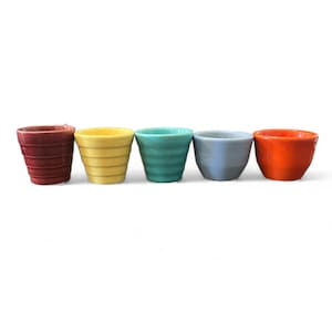 May include: Five small, colorful ceramic pots in a row. The pots are in shades of red, yellow, teal, gray, and orange. Each pot has a ribbed design around the exterior. The pots are empty and sit on a white surface.