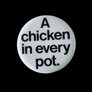 May include: A white button with the phrase "A chicken in every pot" printed in bold black letters. The button is round and set against a black background.