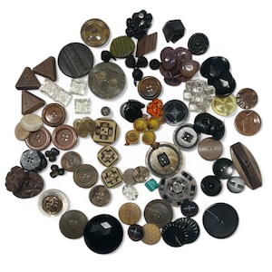 May include: A large collection of assorted buttons in various shapes, sizes, and materials. The assortment includes round, square, triangular, and geometric buttons in shades of black, brown, tan, clear, and metallic tones with diverse textures.