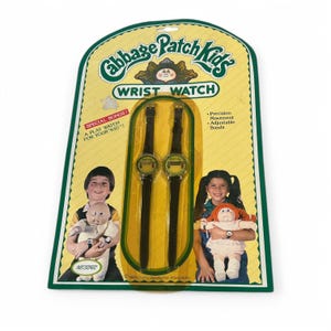 May include: Vintage Cabbage Patch Kids wrist watch set on a yellow and green card. The packaging features the Cabbage Patch Kids logo, the words "Wrist Watch", and images of children with dolls. The watch has a black band.