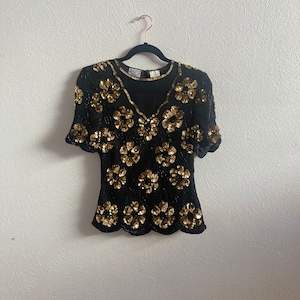 Small gold flower sequin design on black silk top