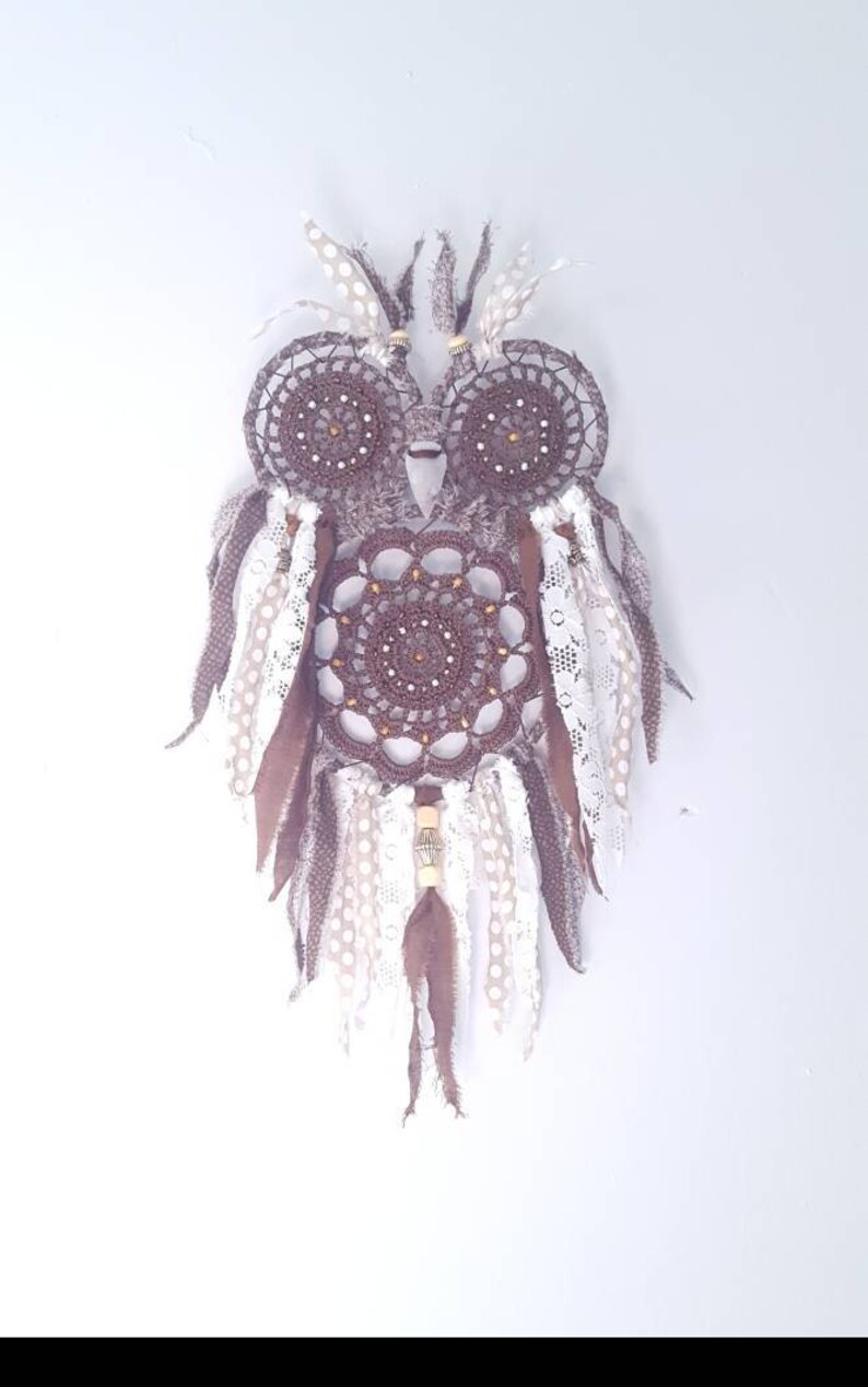 May include: A brown crocheted owl dreamcatcher with white and brown feathers and lace trim.