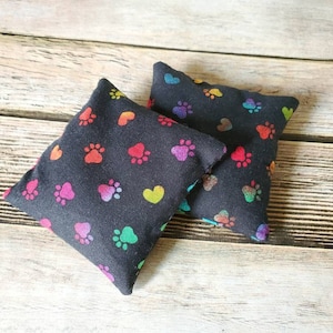 May include: Two black fabric pillow covers with a rainbow paw print and heart pattern.