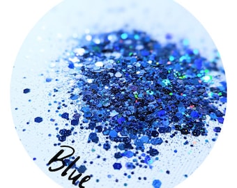 May include: A close-up of a pile of blue glitter in various shapes and sizes. The glitter is scattered on a white surface and the word "Blue" is written in cursive in the lower left corner.