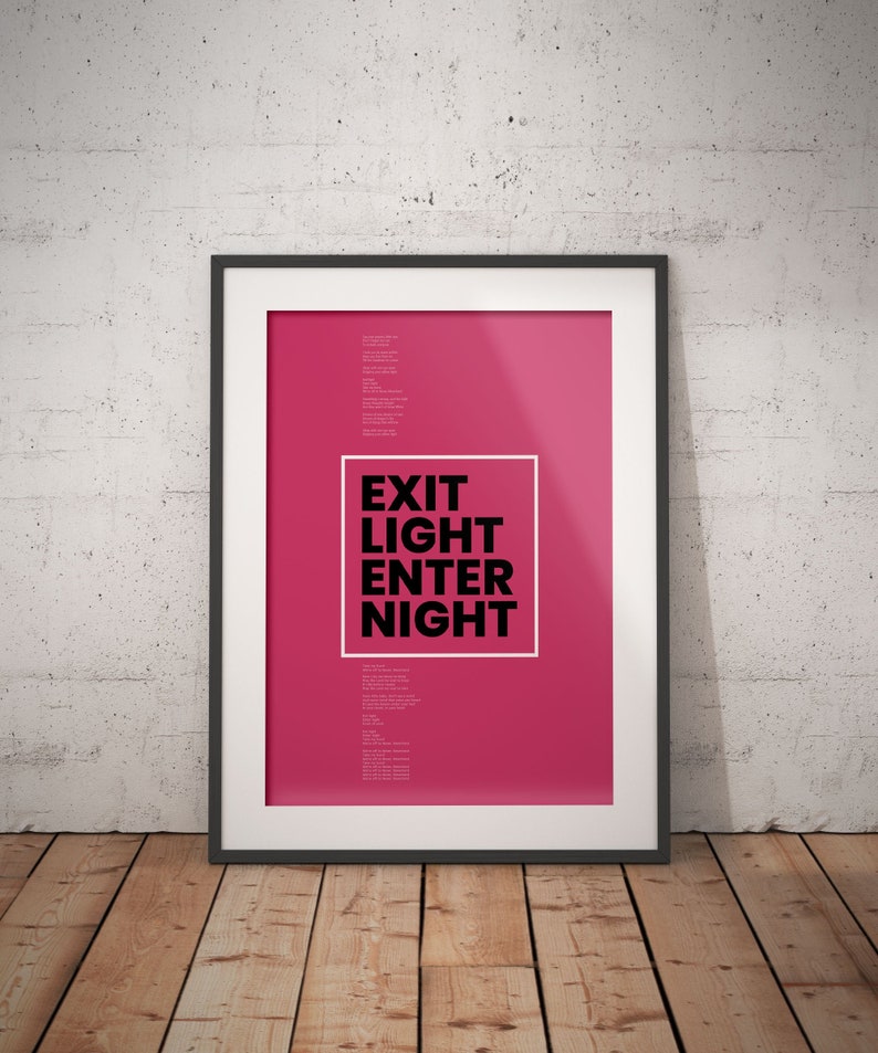 Op de afbeelding: Een ingelijste poster met een roze achtergrond en zwarte tekst die "EXIT LIGHT ENTER NIGHT" luidt.