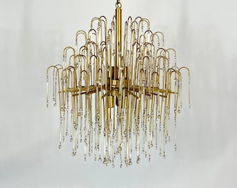 May include: A gold chandelier with a cascading design of clear glass rods and crystal beads. The chandelier is suspended from a chain.