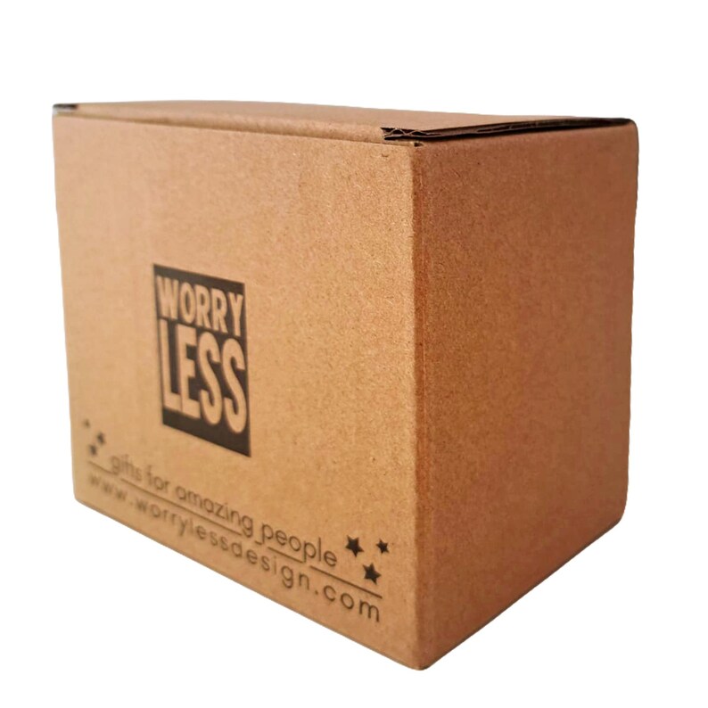 May include: A brown cardboard box with the words "Worry Less" in a black square. Below the text are the words "gifts for amazing people" and a website address. The box is on a white background.