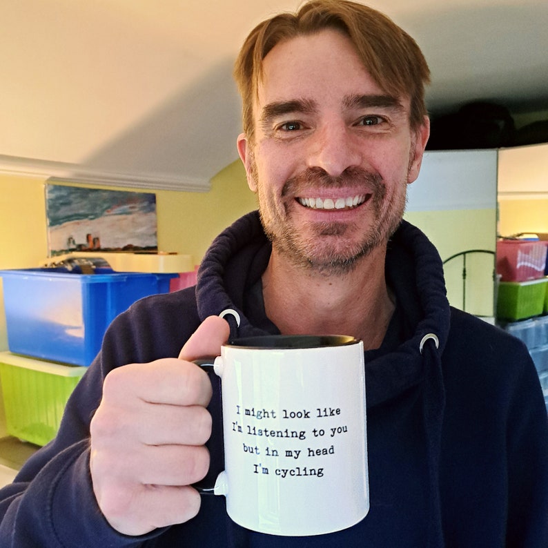 May include: White ceramic mug with a black interior and handle. The mug features the text: "I might look like I'm listening to you but in my head I'm cycling."