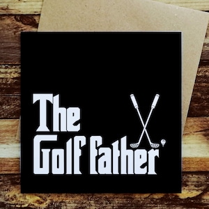 May include: Black greeting card with white text that reads "The Golf Father." The design includes crossed golf clubs and a golf ball. The card is on a brown envelope.