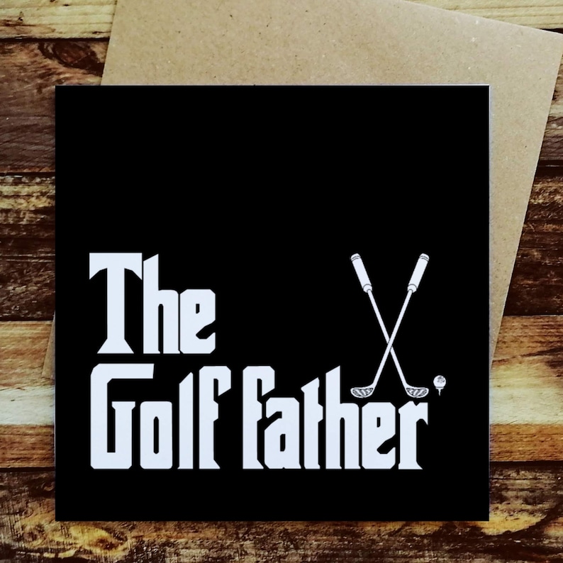 May include: Black greeting card with white text that reads "The Golf Father." The design includes crossed golf clubs and a golf ball. The card is on a brown envelope.