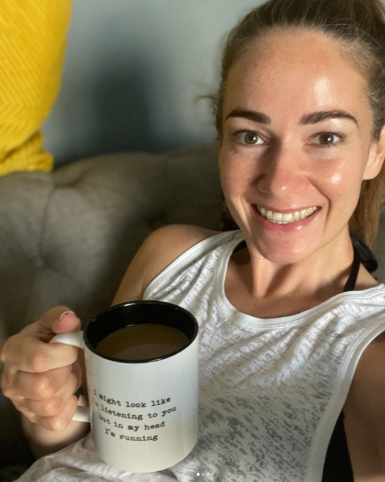 May include: White ceramic coffee mug with black rim and handle. The mug has black text that reads "I might look like I'm listening to you but in my head I'm running."