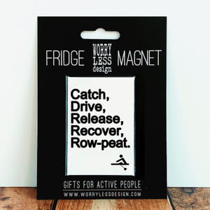 May include: A black fridge magnet with a white rectangular insert. The insert features the text "Catch, Drive, Release, Recover, Row-peat." and a small rowing illustration. The magnet is labelled "Gifts for Active People."