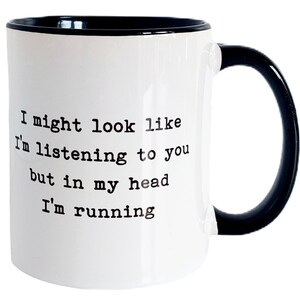 May include: White ceramic mug with a black rim and handle. The mug has black text that reads "I might look like I'm listening to you but in my head I'm running."