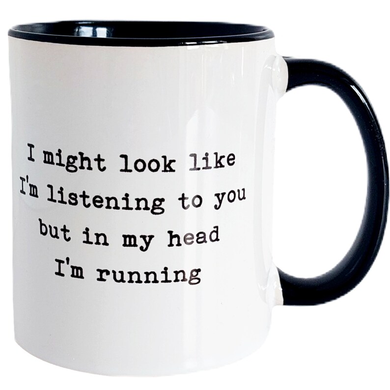 May include: White ceramic mug with a black rim and handle. The mug has black text that reads "I might look like I'm listening to you but in my head I'm running."