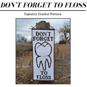 Puede incluir: Un patrón de crochet de tapicería en blanco y negro con el texto "DON'T FORGET TO FLOSS" y un gráfico de un diente. El patrón se muestra al aire libre, colgado de un poste de madera. El patrón es de Cody Crochets.