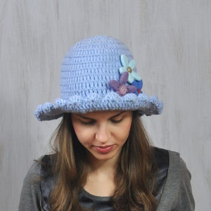 May include: A light blue crocheted hat with a wide brim and flower embellishments.