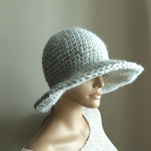 May include: A light gray crocheted sun hat with a wide brim. The hat is made with a textured stitch and has a subtle blue and white color variation.
