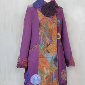 May include: A purple coat with a colorful patterned lining and crocheted embellishments. The coat has a high collar and a button closure.