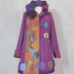 May include: A purple coat with a colorful crocheted collar and trim. The coat has a patchwork design on one side and a solid purple color on the other side.