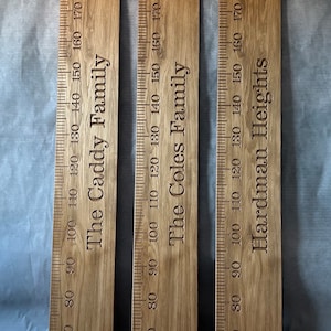 May include: Three wooden growth charts with measurements in centimetres. The charts are labelled "The Caddy Family", "The Coles Family", and "Hardman Heights".