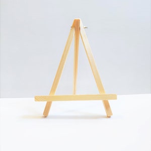 Puede incluir: Un pequeño caballete de madera, perfecto para exhibir pequeñas obras de arte o fotos. El caballete está hecho de madera natural y tiene un diseño simple.