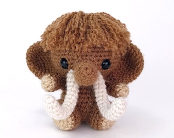 Peut inclure: Un mammouth en peluche crocheté marron avec des défenses en crochet blanc et des yeux noirs. Le mammouth a une crinière brune et moelleuse.